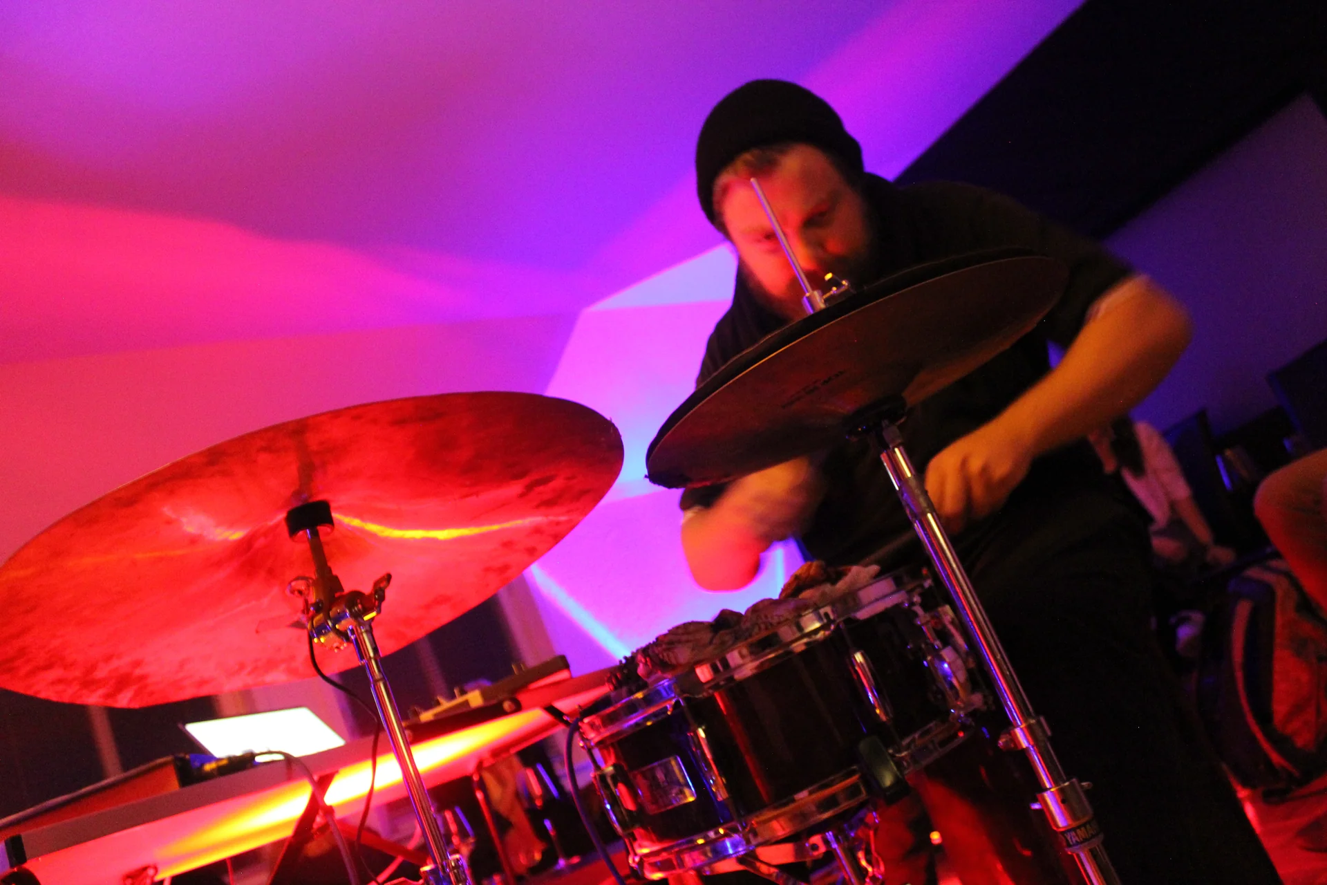 A low-angle view of Markus Zink performing behind cymbals and drums