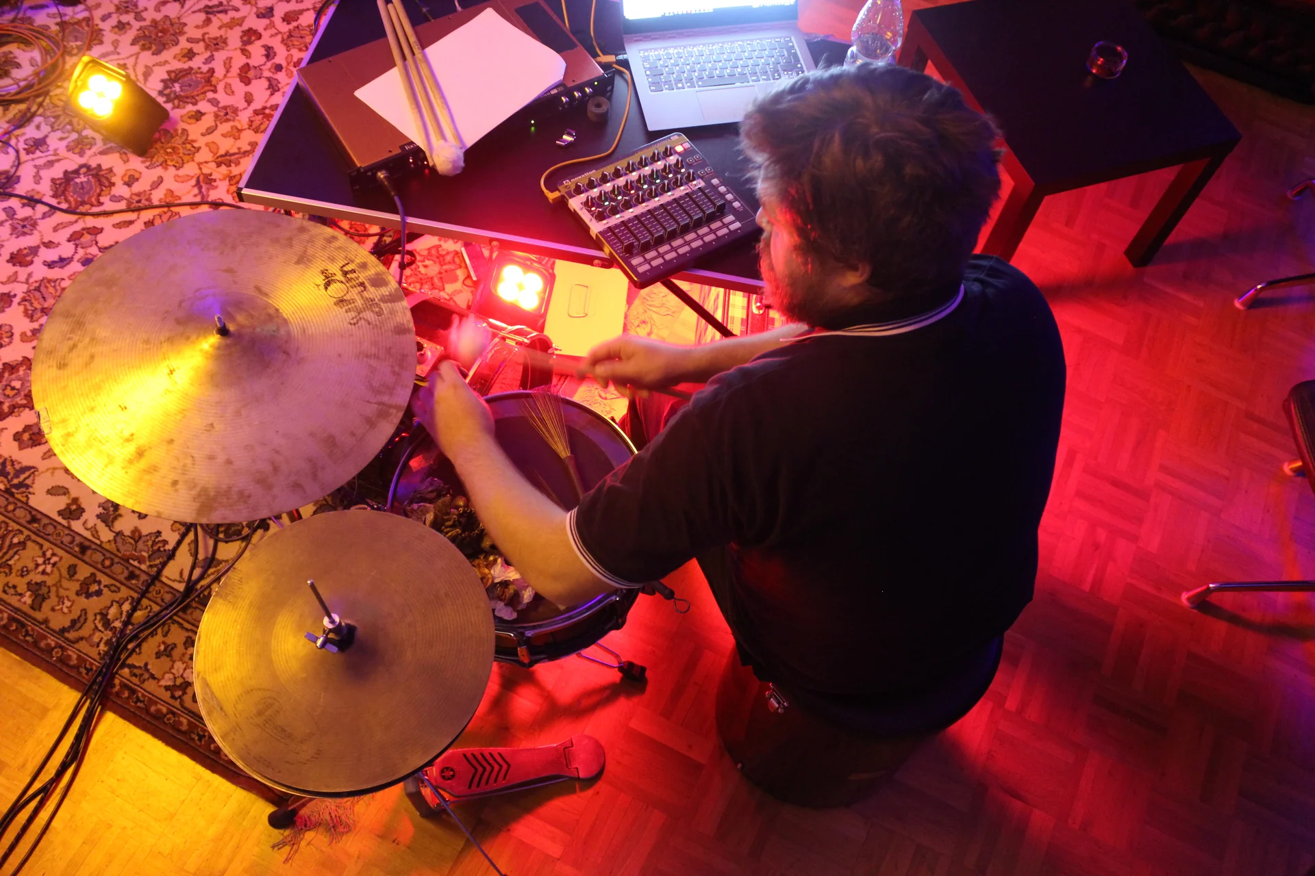 An overhead view of Markus Zink playing drums beside a laptop and electronic equipment