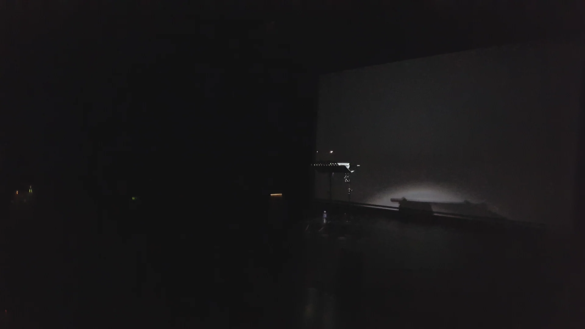 An electronic percussion stand and projection screen on a dark stage